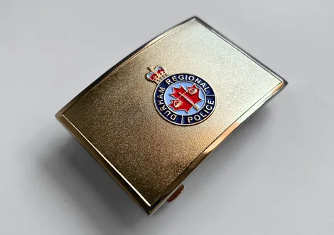 Durham Regional Police badge with crown emblem on a metallic gold background. Example of a custom belt buckle.