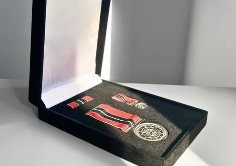 Open black velvet box displaying a medal set with red, white, and black striped ribbons.
