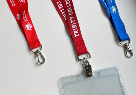 Three lanyards with clips on a white surface, one with an attached clear badge holder. Examples of lanyards.