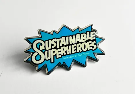 Blue starburst-shaped pin with the text 'Sustainable Superheroes powered by Suxseed'.